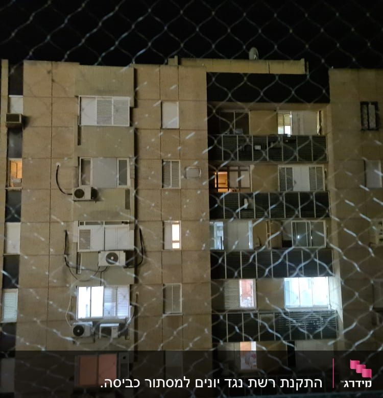 רשת מתכת מול בניין מגורים בלילה